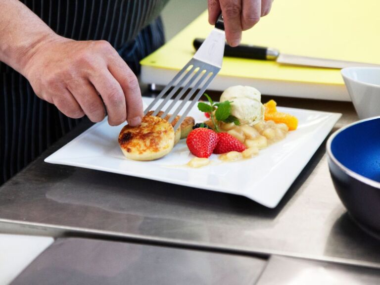 Ein Koch richtet das Essen auf dem Teller an